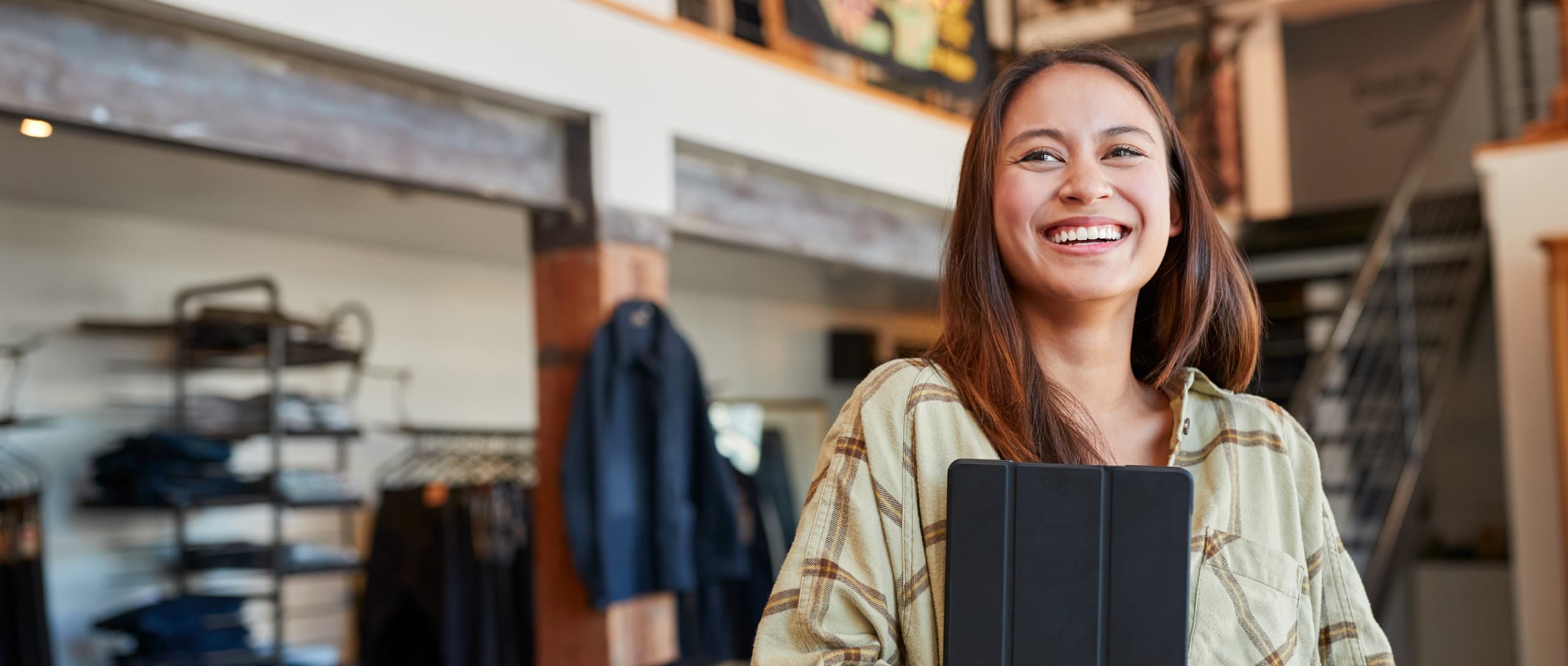 woman smiling and holding an ipad in a clothing store